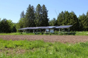Array of four solar panels at the edge of a farmer's field